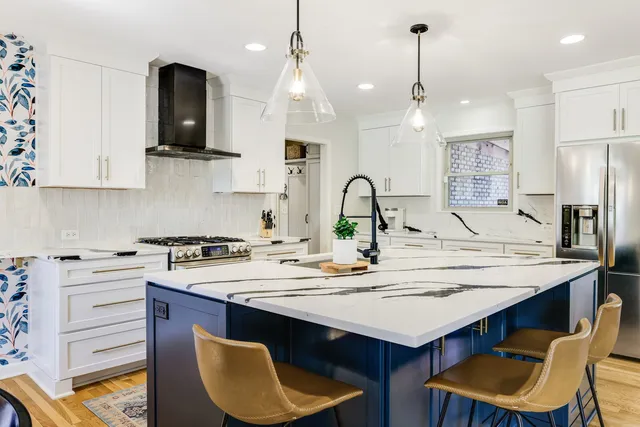 a kitchen with stainless steel appliances granite countertop a sink a stove a refrigerator and white cabinets with wooden floor