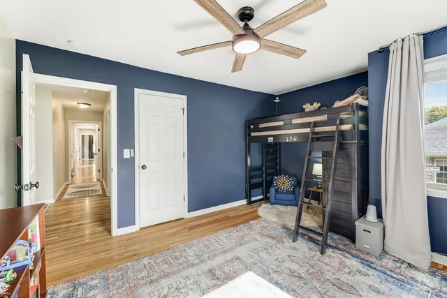 a bedroom with a bed a dresser and a large mirror next to a window