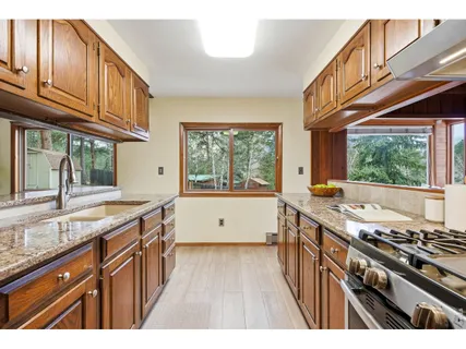a kitchen with stainless steel appliances granite countertop a stove a sink dishwasher and cabinets with wooden floor