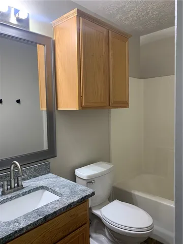 a bathroom with a granite countertop sink toilet and shower