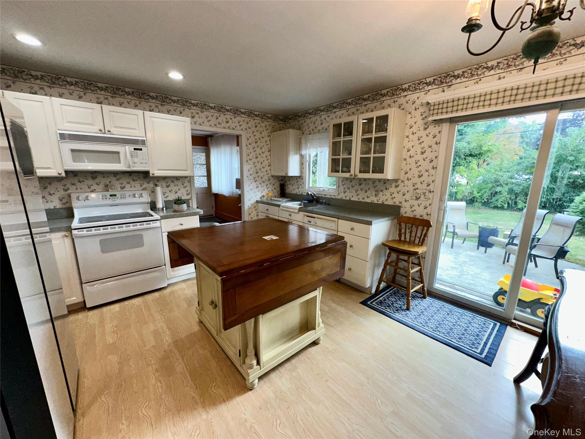 406 Moriches Road St. James, NY 11780 - Photo 2 of 28 a kitchen with kitchen island a stove a refrigerator and a dining table with wooden floor