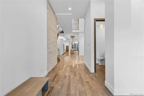 a view of a hallway with wooden floor and a bathroom