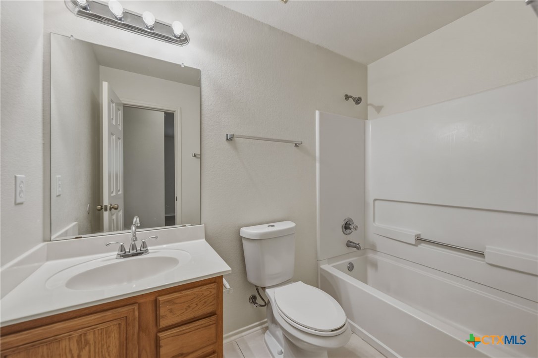 109 Comal Cove Elgin, TX 78621 - Photo 30 of 34 a bathroom with a granite countertop toilet a sink and a bathtub