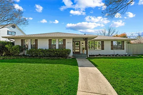 a view of a house next to a yard with plants and trees