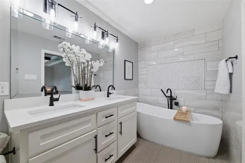 a bathroom with a double vanity sink mirror and bathtub