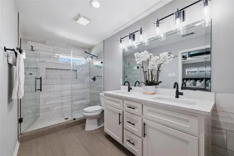 a bathroom with a double vanity sink toilet and shower