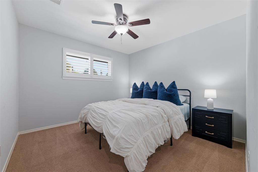 10717 Ferndale Road Dallas, TX 75238 - Photo 25 of 36 a bedroom with a bed and a chandelier