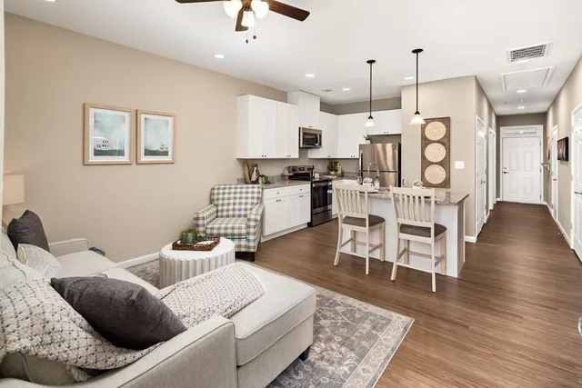 a living room with furniture kitchen view and a wooden floor