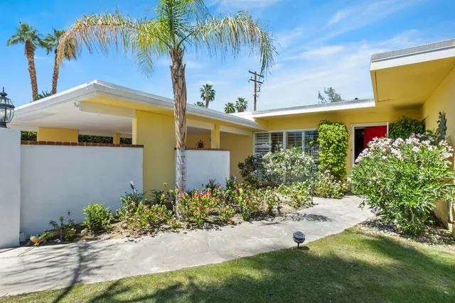 a front view of a house with a yard and potted plants
