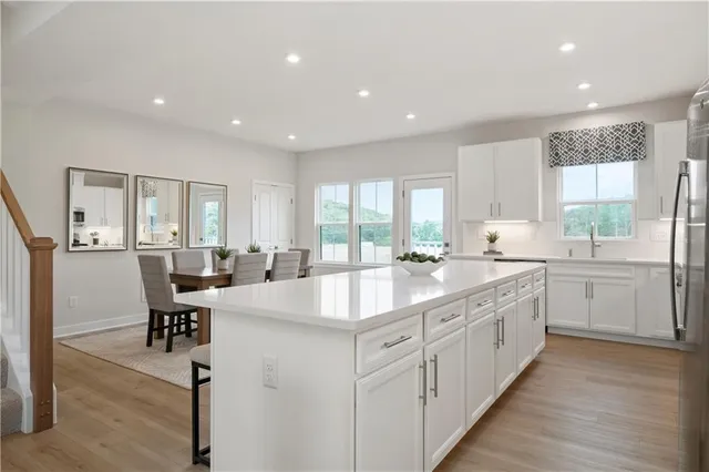 a large kitchen with kitchen island a sink white cabinets and wooden floor