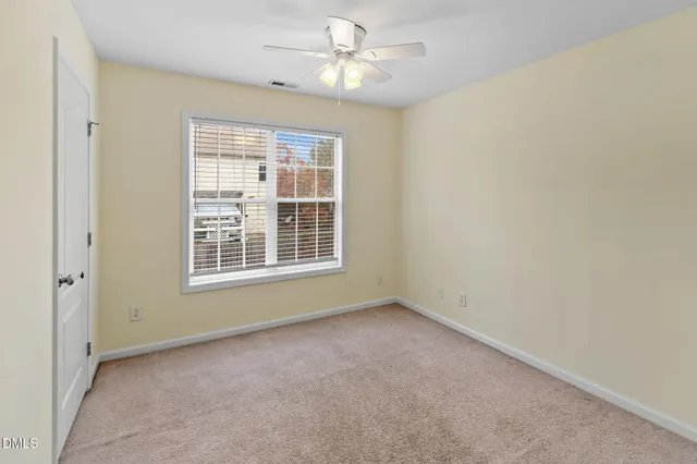 an empty room with chandelier fan and windows