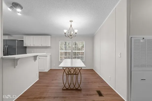 a view of a hallway with wooden floor and a kitchen