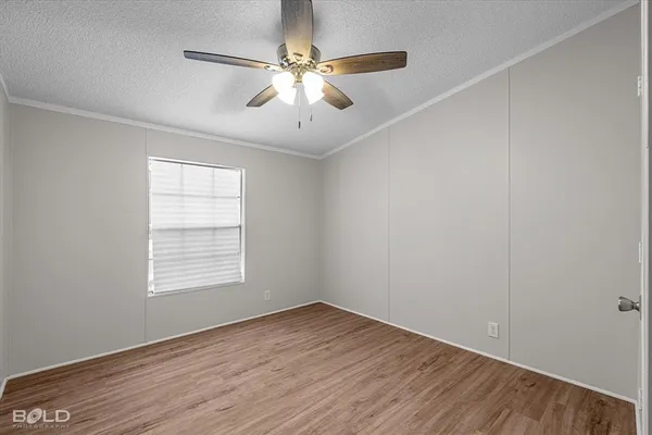 an empty room with wooden floor chandelier fan and windows