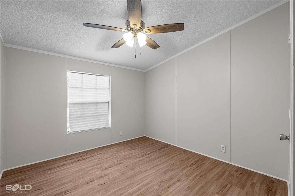 171 7 Pines Road Benton, LA 71006 - Photo 26 of 39 an empty room with wooden floor chandelier fan and windows