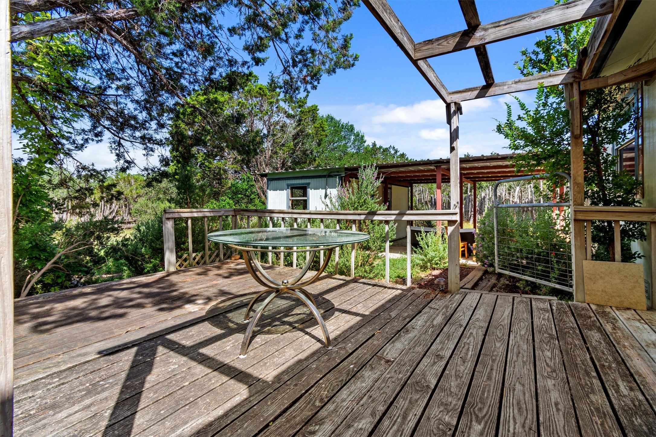 6 El Sol Road Wimberley, TX 78676 - Photo 17 of 20 An inviting wood deck extends into the verdant landscape, perfect for serene outdoor relaxation.