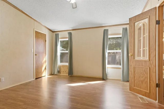 a view of an empty room with wooden floor and a window