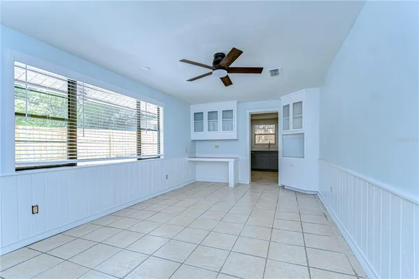 a view of an empty room with a window and kitchen view