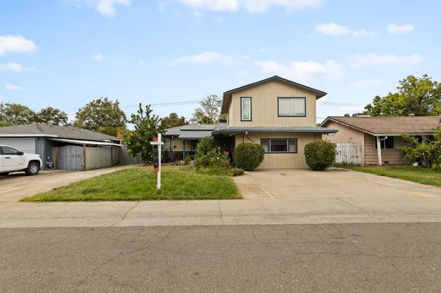 a front view of a house with a garden and trees
