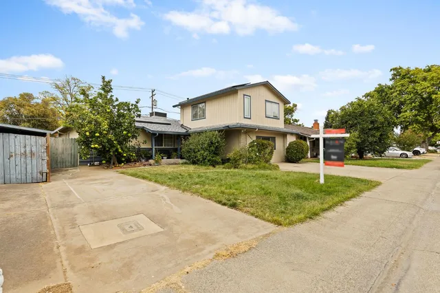 a view of a house next to a yard with road and trees