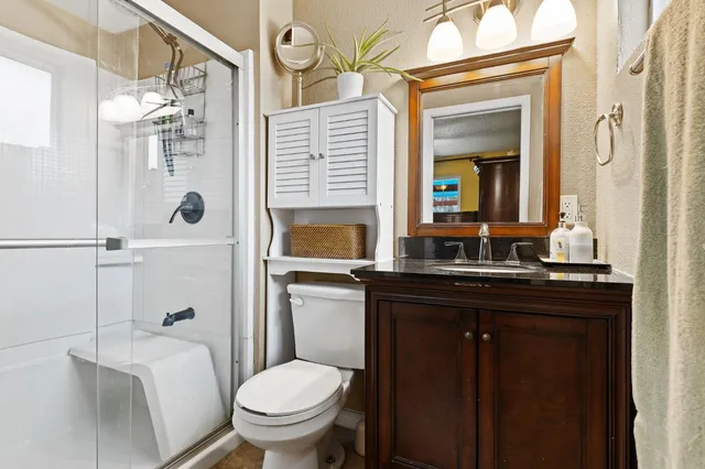 a bathroom with a granite countertop toilet a sink and a mirror