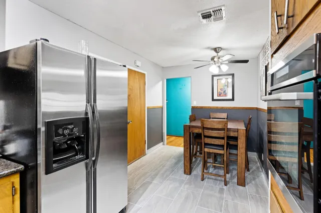a kitchen with stainless steel appliances kitchen island granite countertop a refrigerator and a stove top oven