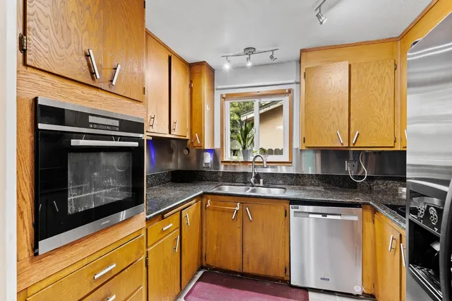 a kitchen with granite countertop stainless steel appliances a stove sink and microwave