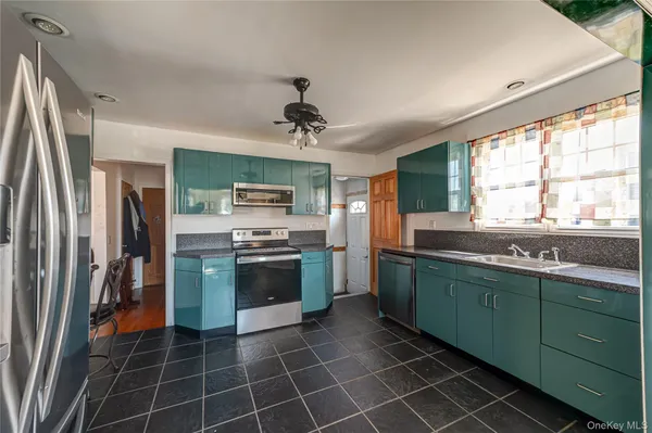 a kitchen with stainless steel appliances granite countertop a sink a stove a refrigerator cabinets and a window