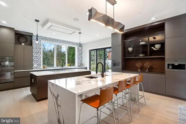 a dining hall with stainless steel appliances kitchen island a table and chairs in it