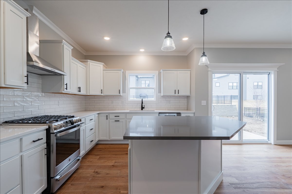 5206 Finlen Lane Bloomington, IL 61705 - Photo 13 of 40 a kitchen with stainless steel appliances granite countertop a stove a sink and white cabinets with wooden floor