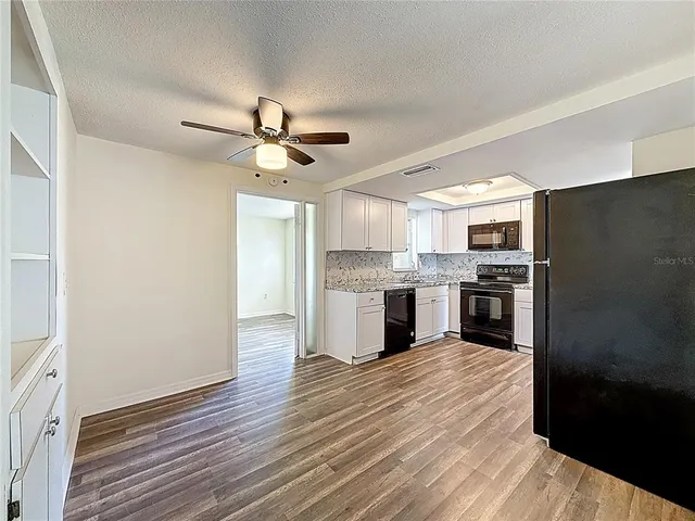 a kitchen with a refrigerator and white cabinets