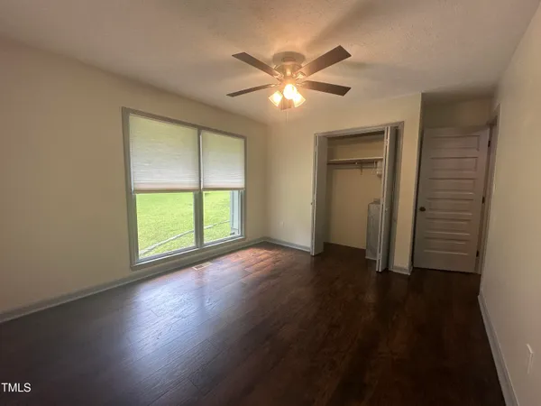 a view of an empty room with wooden floor and a window