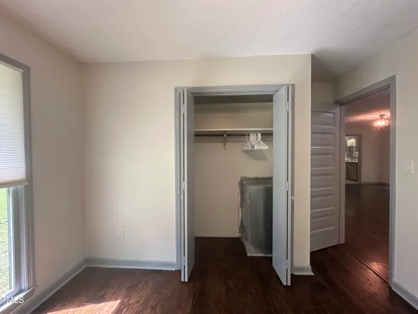 an empty room with wooden floor & closet area