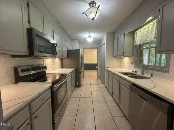 a large kitchen with a stove top oven a sink a counter space and cabinets