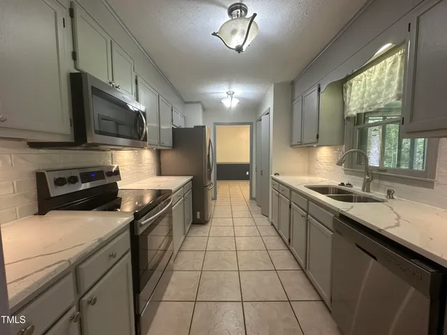 a large kitchen with a stove top oven a sink a counter space and cabinets