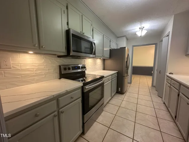 a kitchen with stainless steel appliances granite countertop a refrigerator and a stove top oven