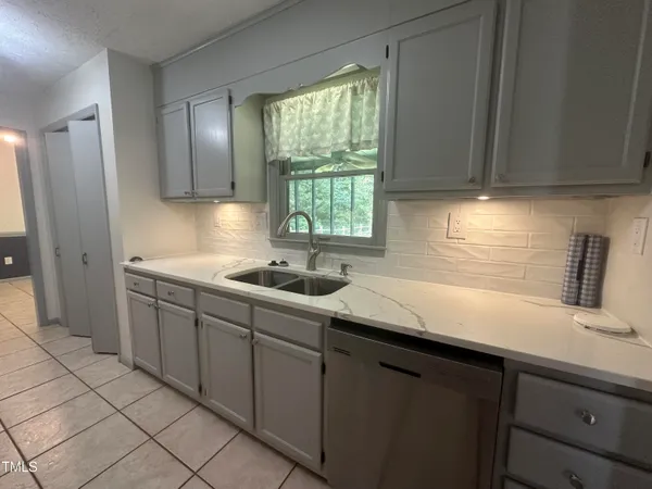 a kitchen with stainless steel appliances granite countertop a sink dishwasher a refrigerator and cabinets with wooden floor