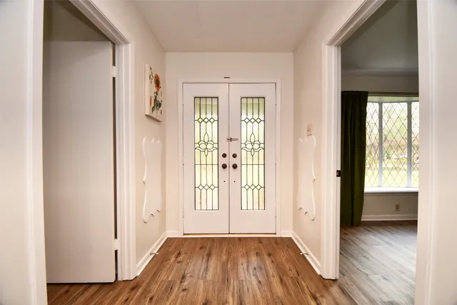 a view of an empty room with window and wooden floor