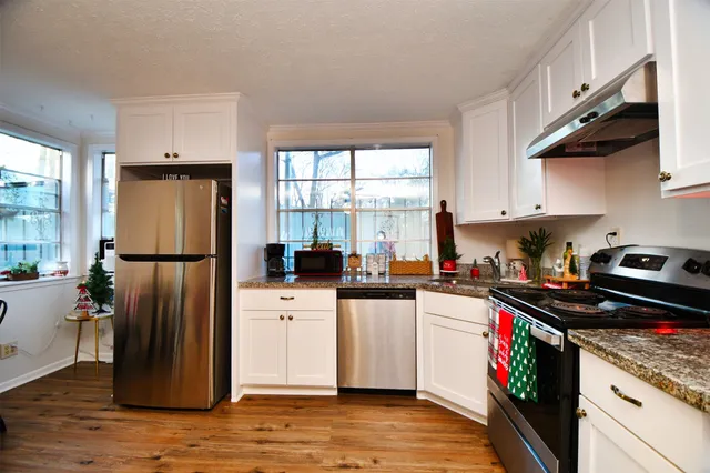 a kitchen with stainless steel appliances granite countertop a refrigerator a sink dishwasher a stove and a refrigerator