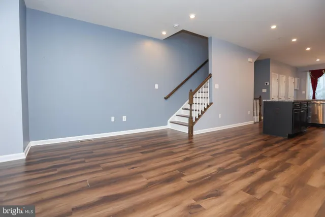 a view of an empty room with wooden floor and stairs