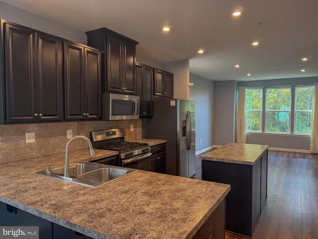 a kitchen with granite countertop kitchen island stainless steel appliances a sink stove and refrigerator