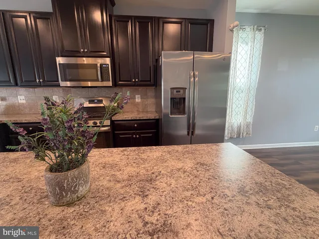 a kitchen with granite countertop a refrigerator and a stove top oven