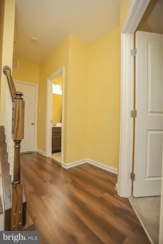 a view of an empty room with wooden floor and a bathroom
