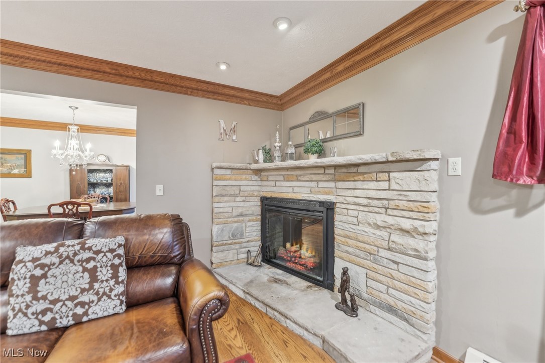 6326 Murray Ridge Road Elyria, OH 44035 - Photo 9 of 49 Living room featuring a fireplace, hardwood / wood-style floors, crown molding, and a notable chandelier