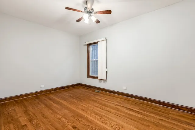 an empty room with a window and a ceiling fan