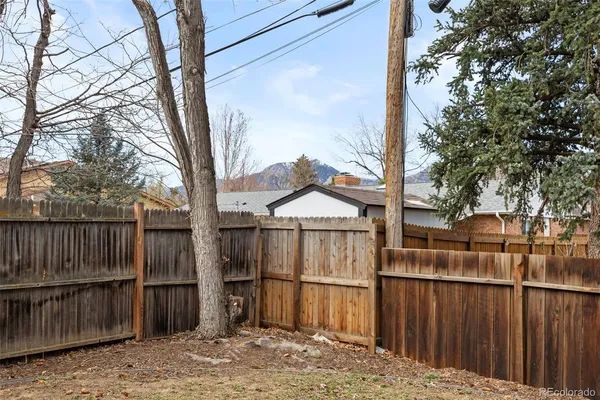 a view of backyard with wooden fence and large trees