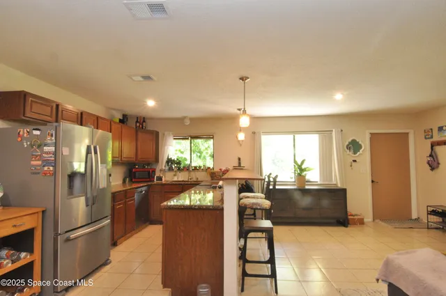 a kitchen with stainless steel appliances granite countertop a refrigerator a sink a stove and a refrigerator with wooden floor