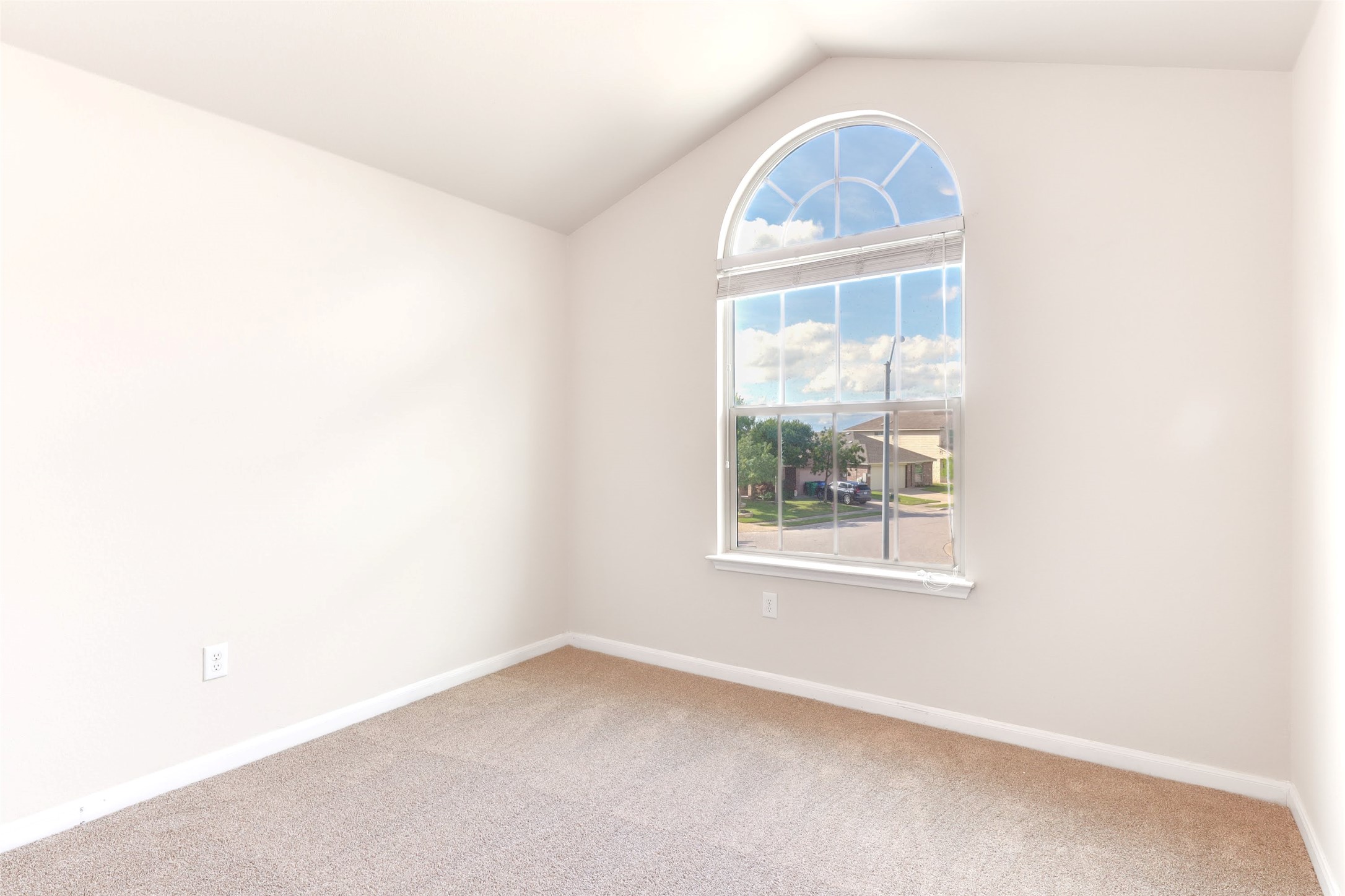 18705 Moreto Loop Pflugerville, TX 78660 - Photo 14 of 21 A quiet, carpeted room features a vaulted ceiling and an arched window overlooking the neighborhood.