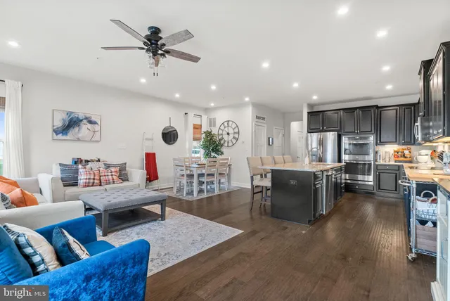a living room with furniture kitchen view and a wooden floor