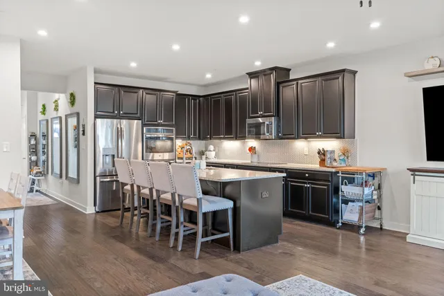 a kitchen with kitchen island granite countertop wooden cabinets a refrigerator a stove a dining table and chairs