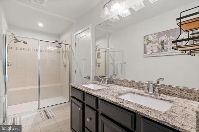 a bathroom with a granite countertop sink a mirror and a shower